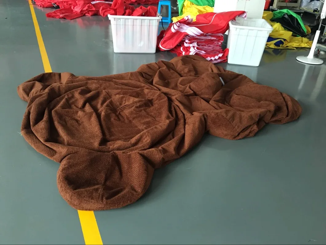 The same bear deflated and lying flat on the floor, folded to the footprint of a large duvet