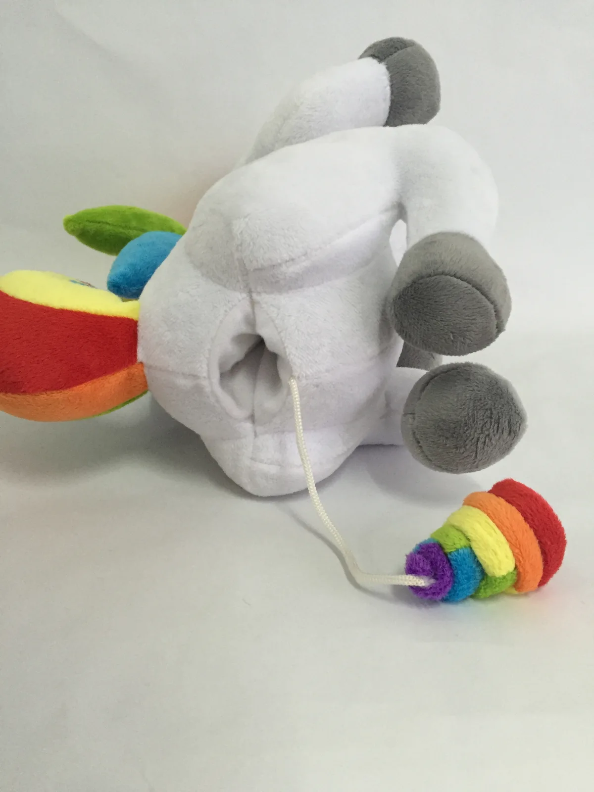 The sample tipped forward to show the opening under its tail, with the white cord running out to the rainbow swirl